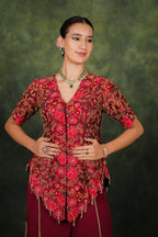 Woman wearing a red and brown patterned blouse with a green background